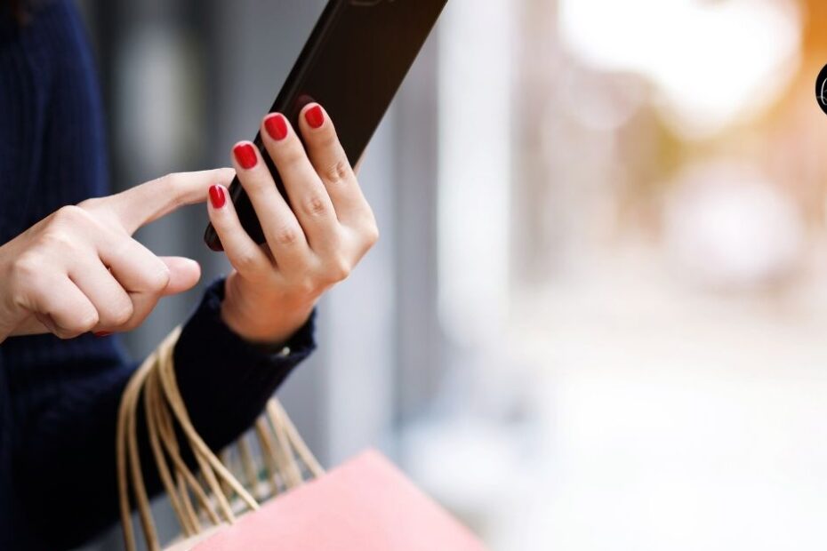 close-up of woman's hands holding smartphone and shopping bag