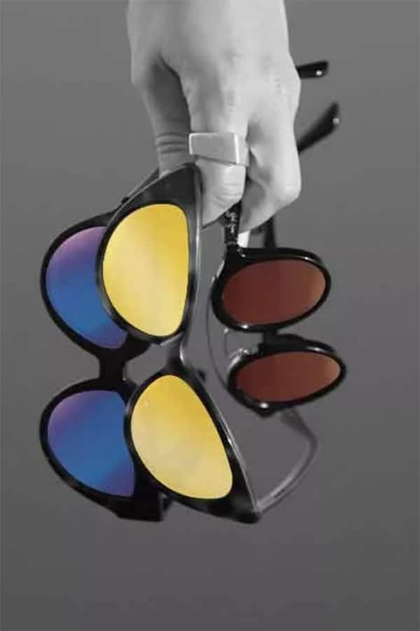 Hand holding sunglasses with different colored lens 