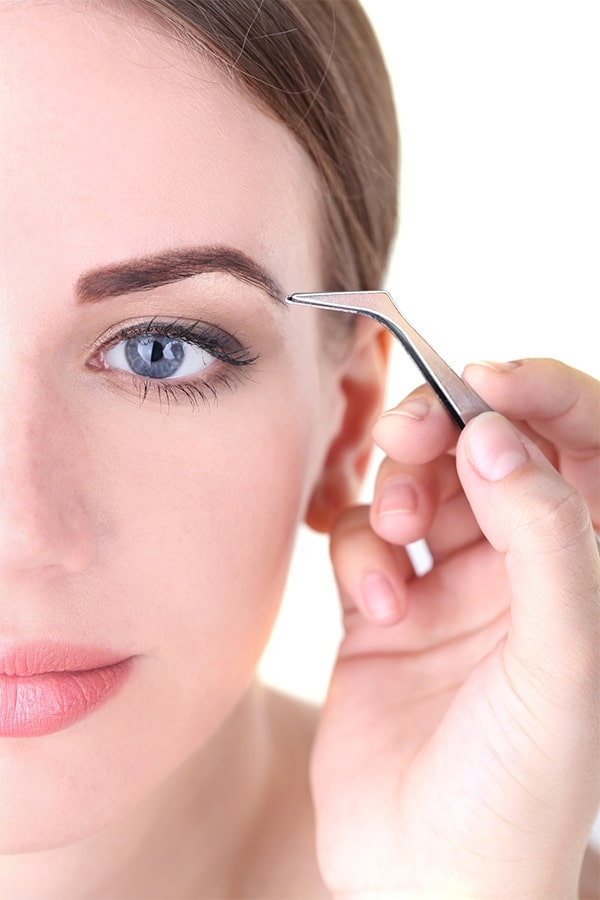 Woman tweezing eyebrows