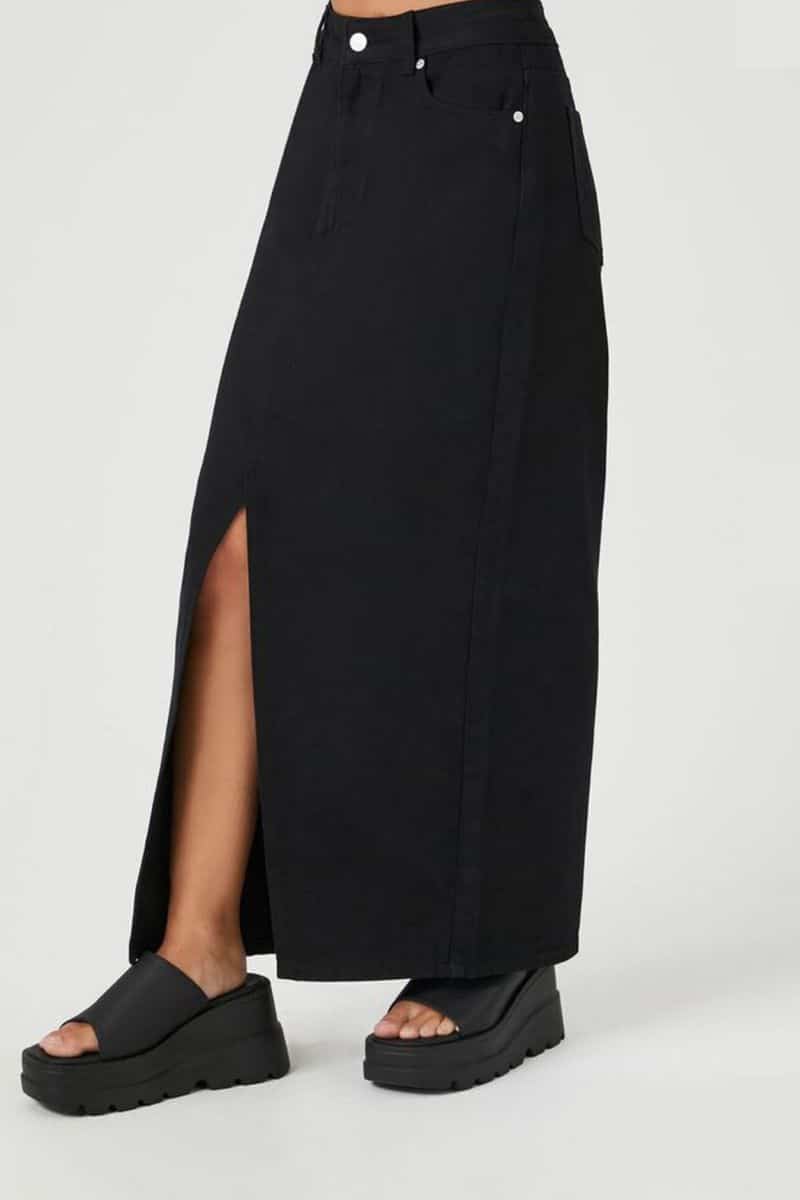 Waist-down view of woman wearing denim maxi skirt in black.