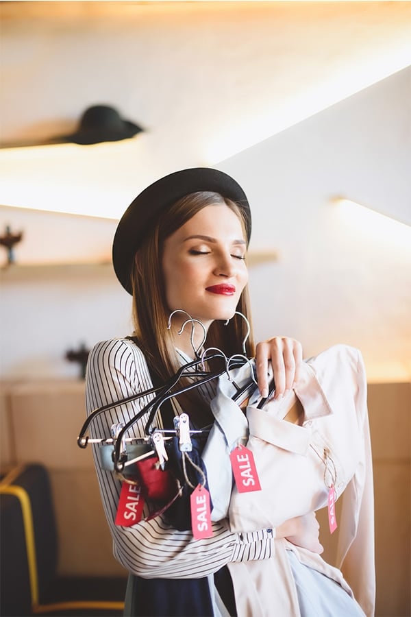 Woman holding clothes with sales tags 