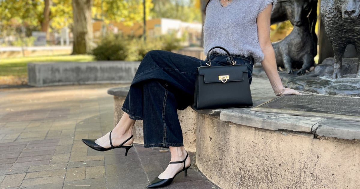 Levantine Layla bag on curb next to stylish woman sitting outside.