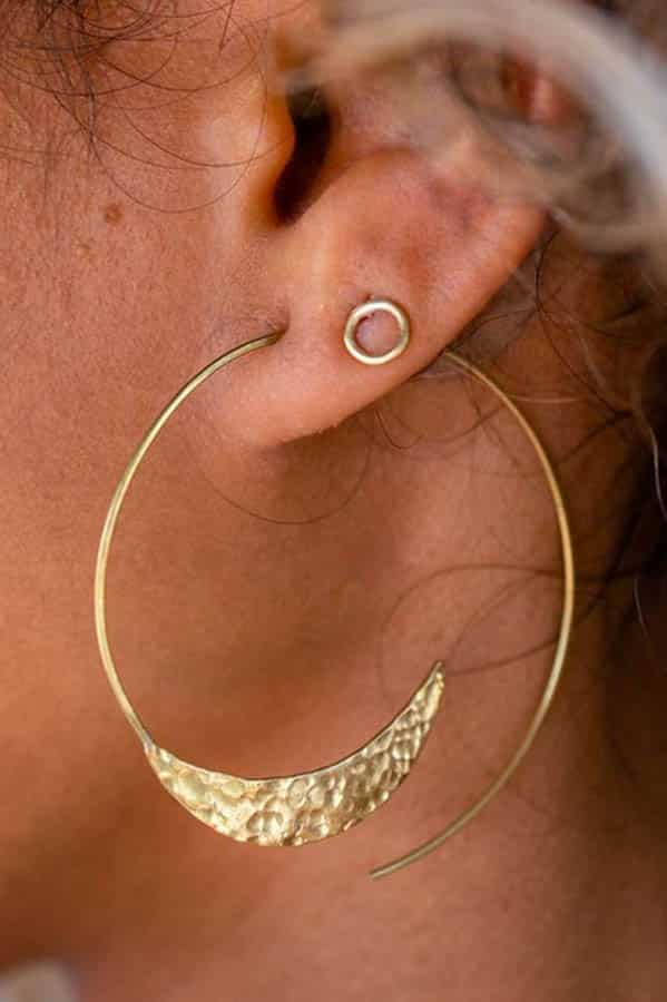 Give good: 9 charity gifts fashion enthusiasts will love 4 Close up of woman's ear, adorned with a curved hoop earring from Purpose Jewelry.