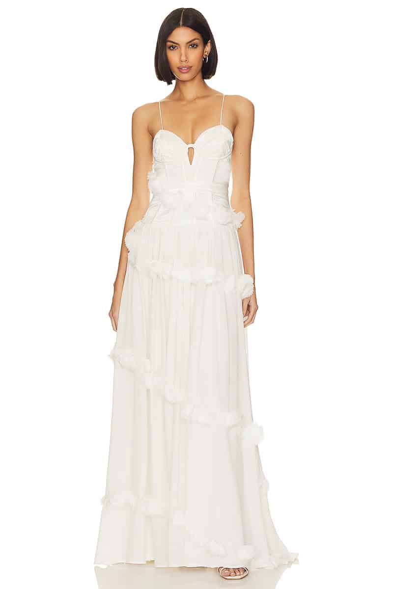 Model wears white strapless dress with embellishments. 