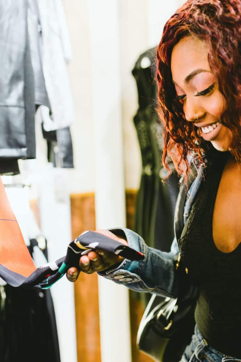Woman looks at price tag on garment to represent shopping at Saks Fifth Avenue's outlet store.