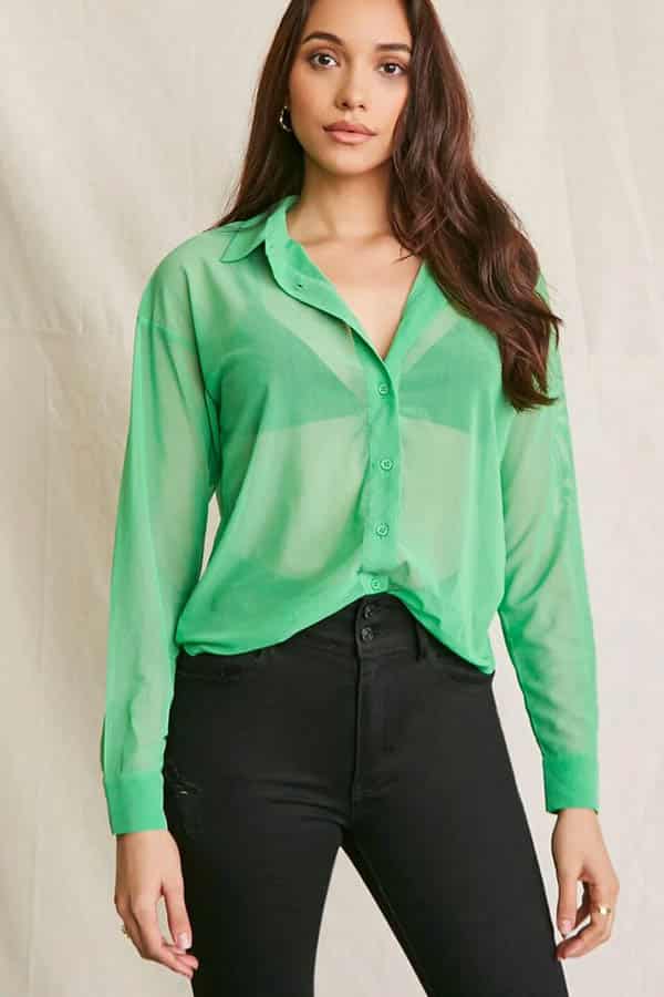 Model wears sheer green buttondown top.
