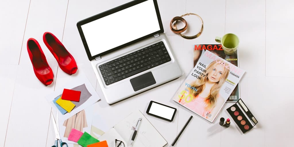 Tumblr fashion blogger's desk: laptop surrounded by magazine, makeup and shoes