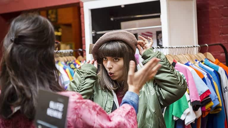 Two people try on vintage clothing in a consignment shop.