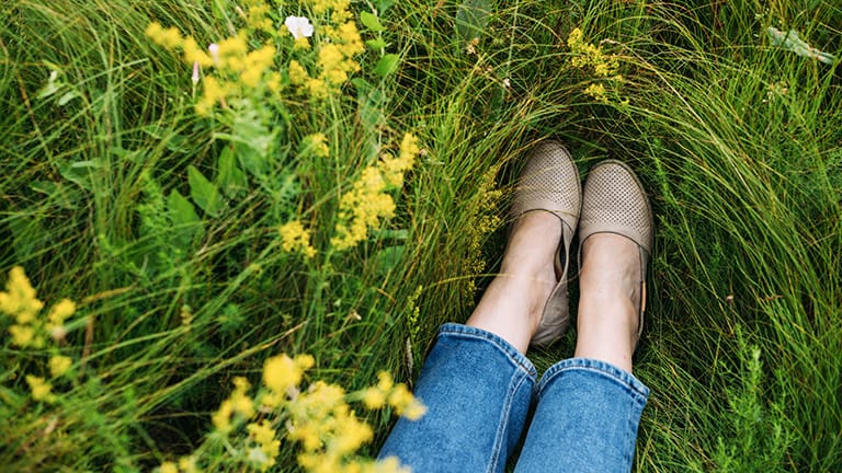 Close up of woman's feet wearing flat shoes in grass.
