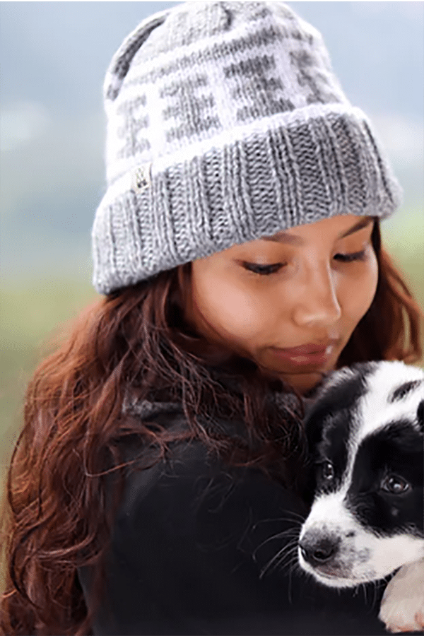 Give good: 9 charity gifts fashion enthusiasts will love 1 Woman holding puppy wears knit beanie from charity brand Fazl.