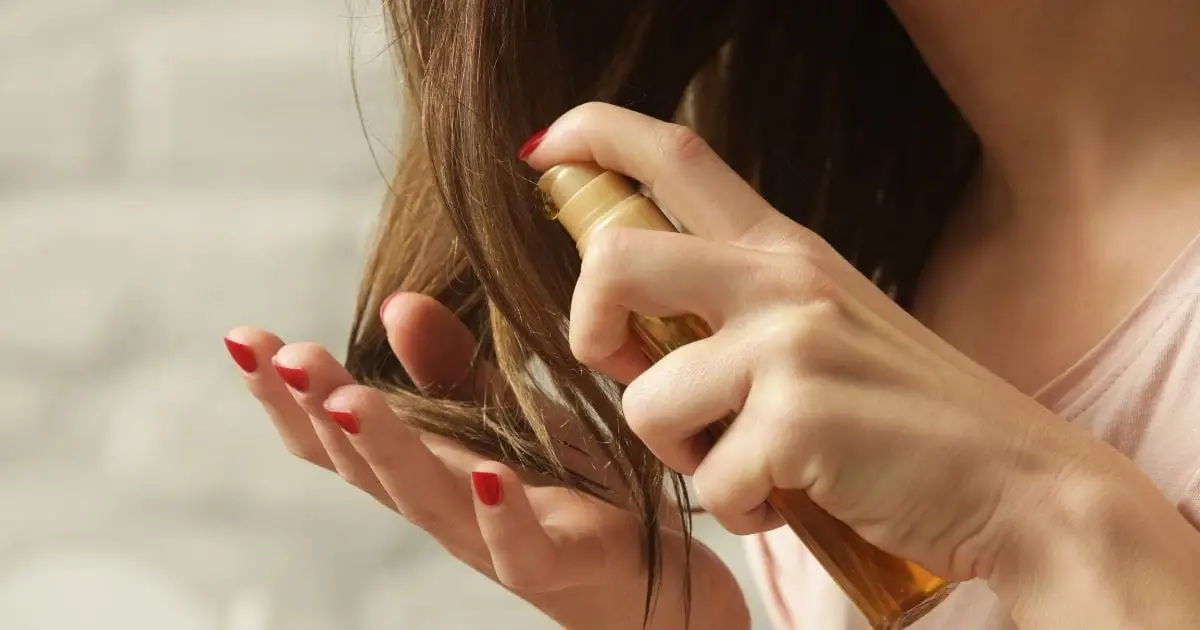 Close-up of woman applying hair product to hair.